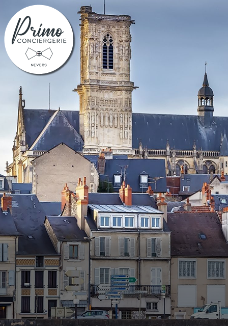 Vue de la cathédrale de Nevers avec des bâtiments historiques en avant-plan.
