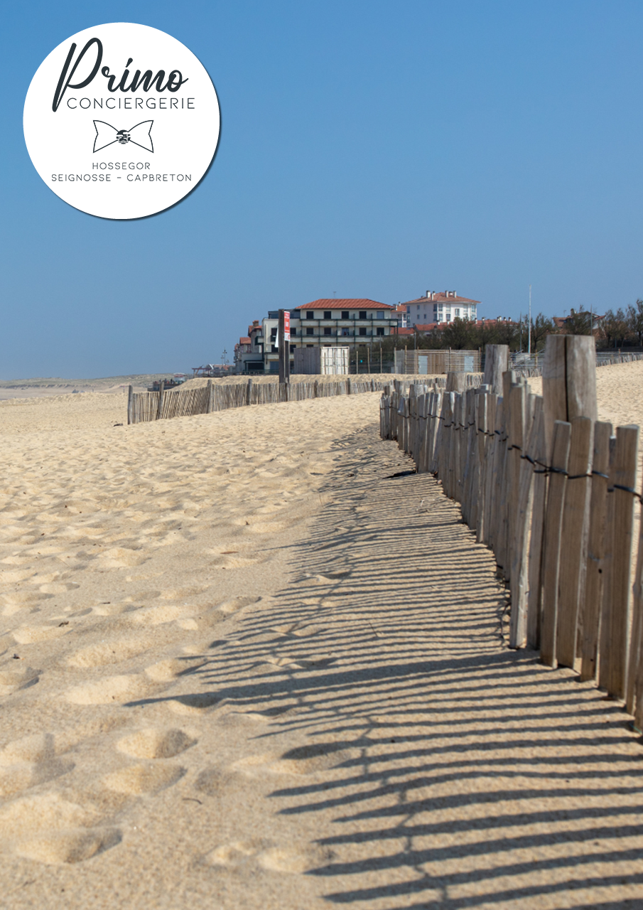 Sentier côtier d'Hossegor bordé de clôtures en bois et vue sur la mer.